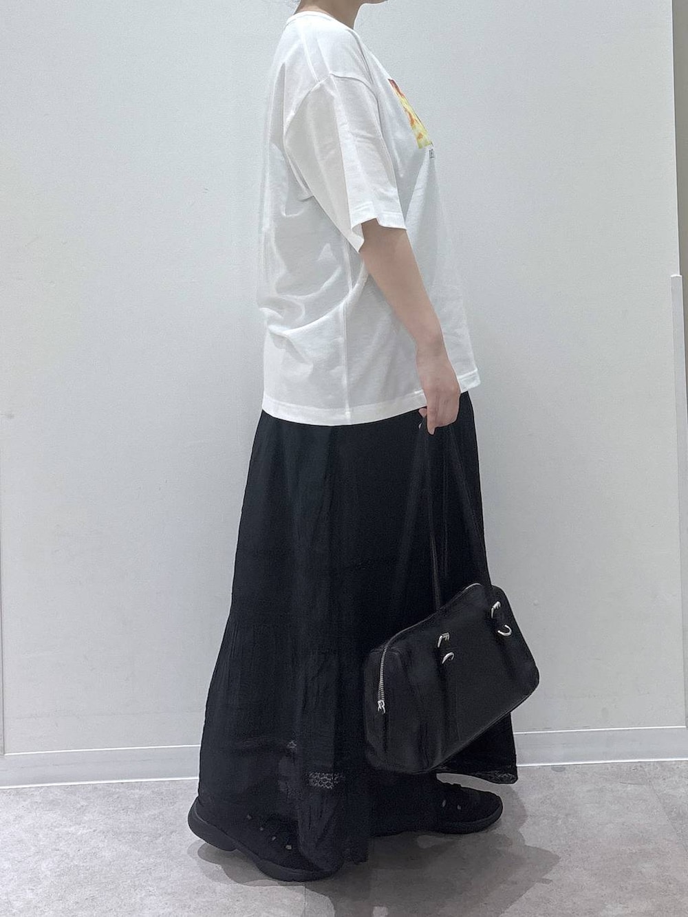 ブラック系のスカート、ブラック系のショルダーバッグ、ホワイト系のTシャツ/カットソーを着用したレディースの春コーディネートの2枚目の写真