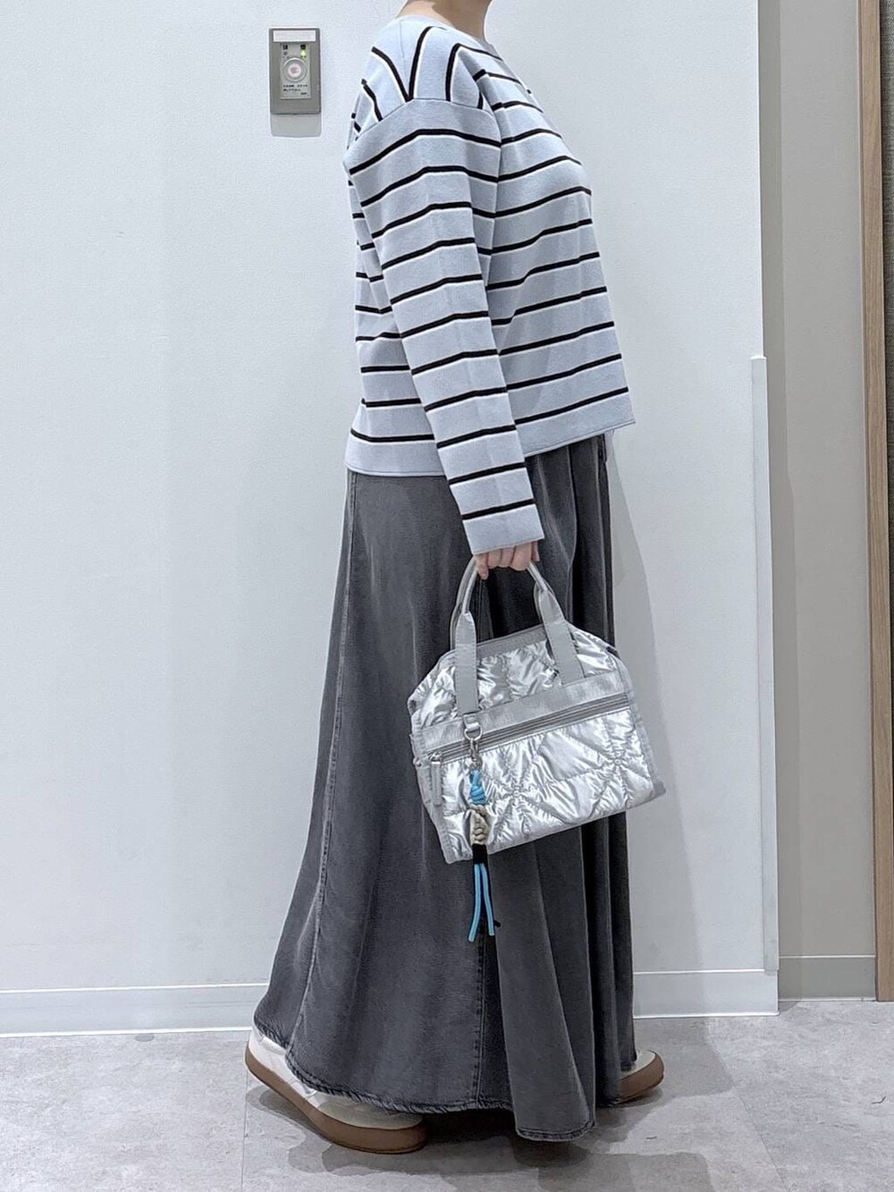 ホワイト系のスニーカー、シルバー系のボストンバッグ、ブルー系のニット/セーターを着用したレディースの春コーディネートの2枚目の写真