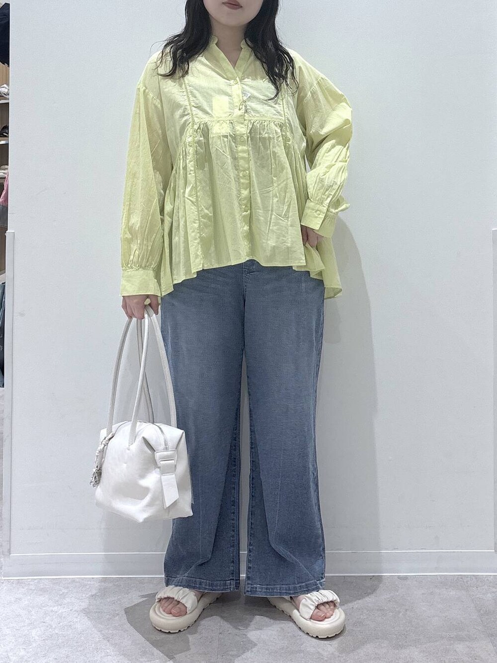 ホワイト系のボストンバッグ、イエロー系のシャツ/ブラウス、ブルー系のデニムパンツを着用したレディースの春コーディネートの4枚目の写真