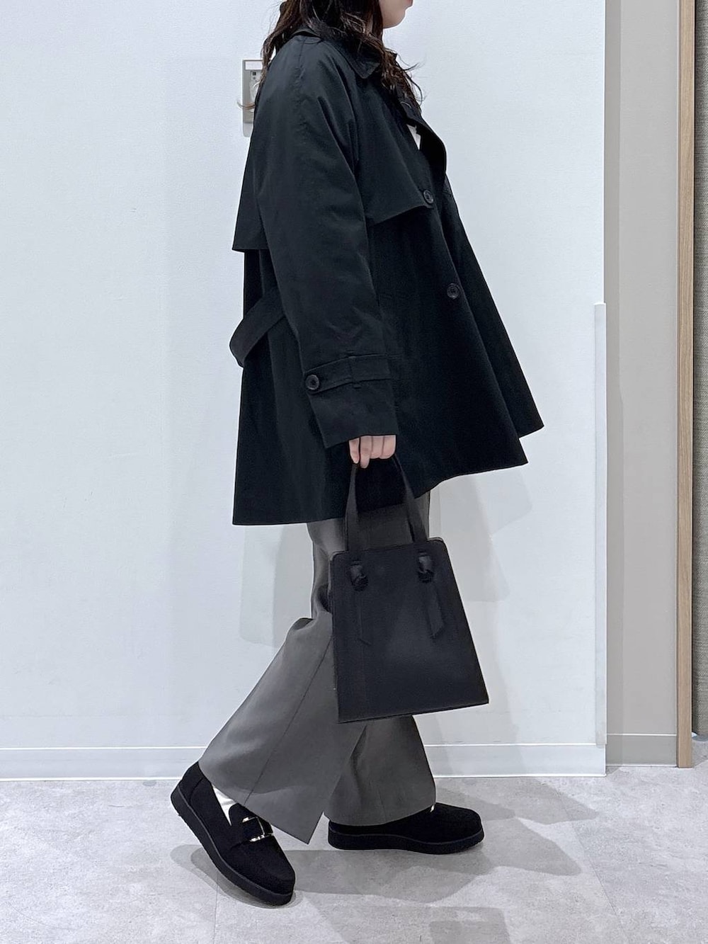 ブラック系のローファー、ブラック系のショルダーバッグ、ブルー系のトレンチコートを着用したレディースの春コーディネートの2枚目の写真