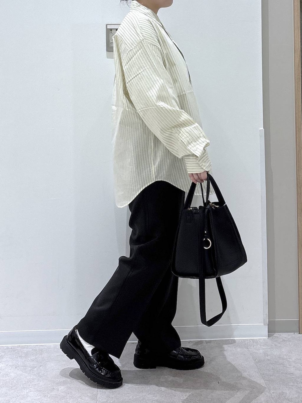 ブラック系のトートバッグ、ブラック系のスラックス、イエロー系のシャツ/ブラウスを着用したレディースの春コーディネートの2枚目の写真