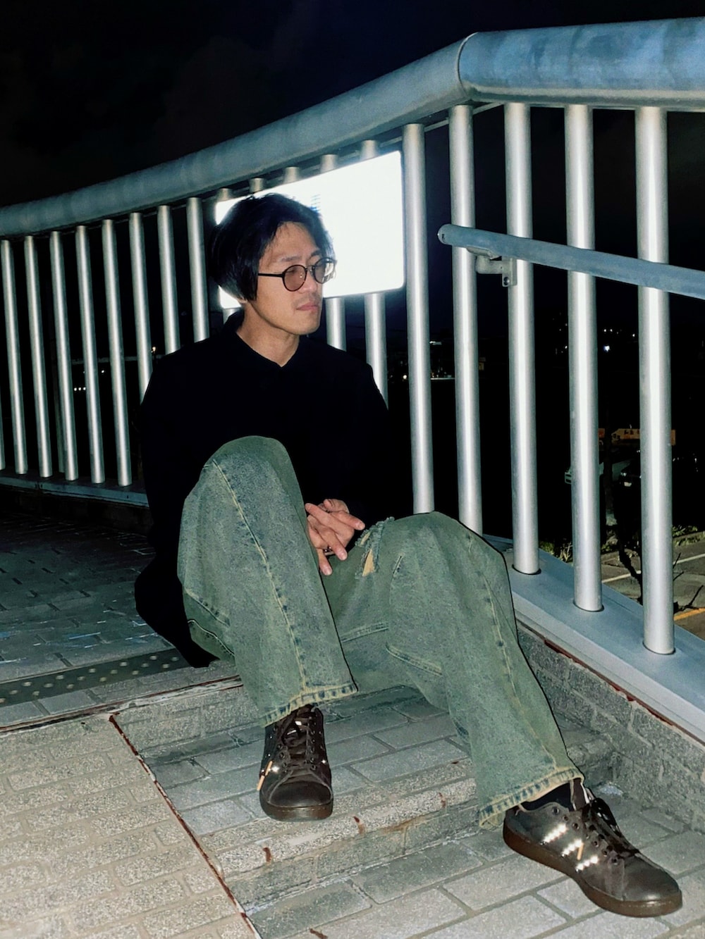 ブルー系のデニムパンツ、ブラウン系のスニーカー、ブラック系のシャツ/ブラウスを着用したメンズの春コーディネートの2枚目の写真