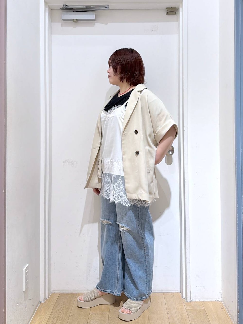 ブルー系のデニムパンツ、ホワイト系のテーラードジャケット、ホワイト系のサンダルを着用したレディースの春コーディネートの2枚目の写真