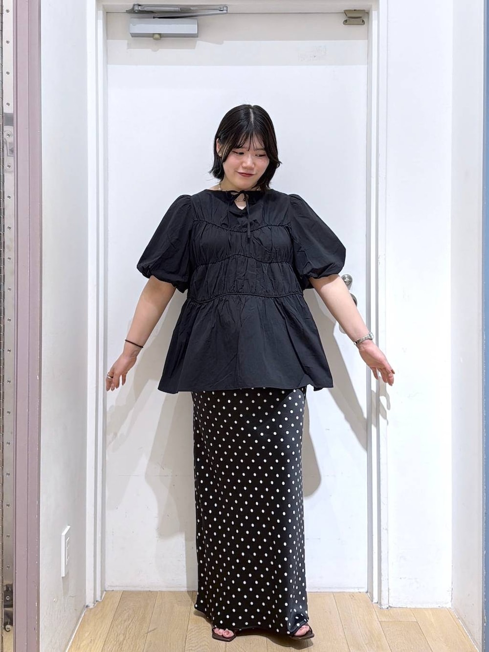 ブラック系のシャツ/ブラウス、ブラック系のスカート、ブラウン系のサンダルを着用したレディースの夏コーディネートの2枚目の写真
