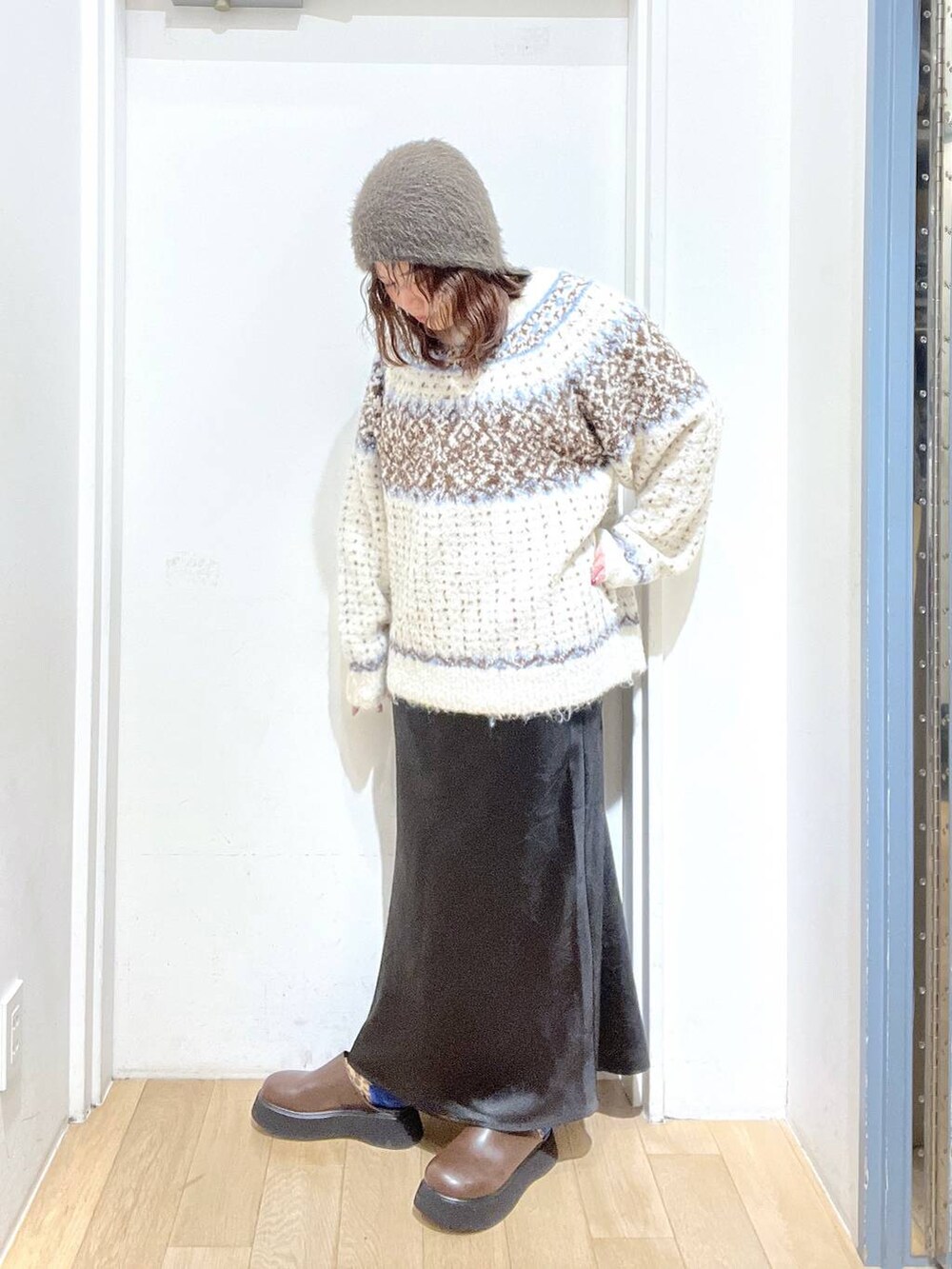 ブラック系のスカート、ブラウン系のサンダル、ホワイト系のニット/セーターを着用したレディースの冬コーディネートの2枚目の写真