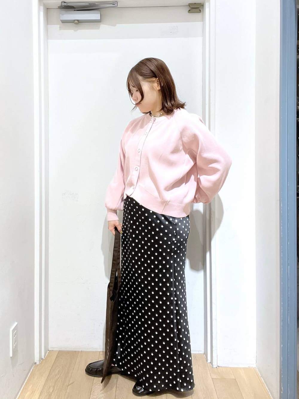 ブラック系のスカート、ブラウン系のトートバッグ、ブラック系のローファーを着用したレディースの冬コーディネートの2枚目の写真