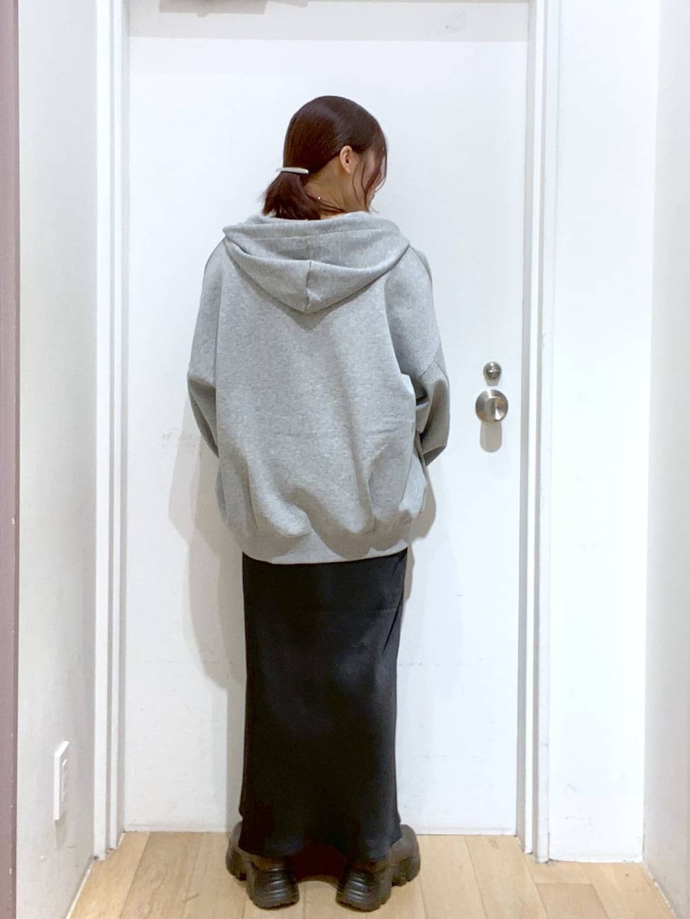 ブラウン系のブーツ、ブラック系のスカート、グレー系のパーカーを着用したレディースの秋コーディネートの3枚目の写真