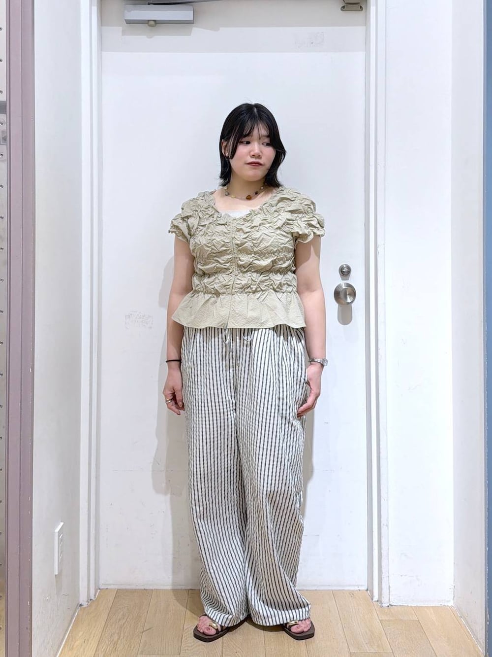 ベージュ系のシャツ/ブラウス、シルバー系のタンクトップ、ブラウン系のサンダルを着用したレディースの夏コーディネートの2枚目の写真