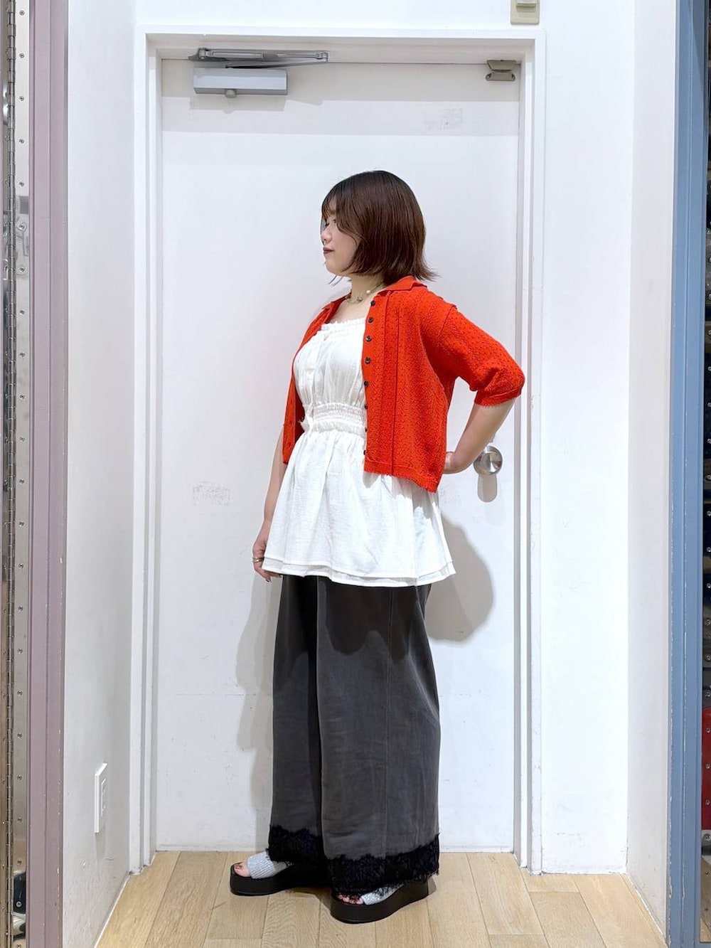 レッド系のカーディガン/ボレロ、ホワイト系のキャミソール、シルバー系のタンクトップを着用したレディースの夏コーディネートの3枚目の写真