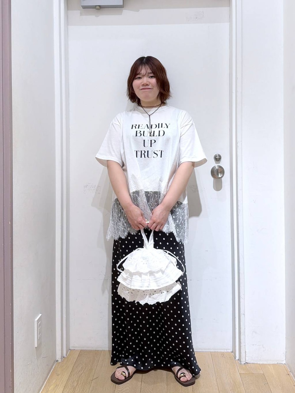 ブラック系のスカート、ブラウン系のサンダル、ホワイト系のハンドバッグを着用したレディースの春コーディネートの5枚目の写真