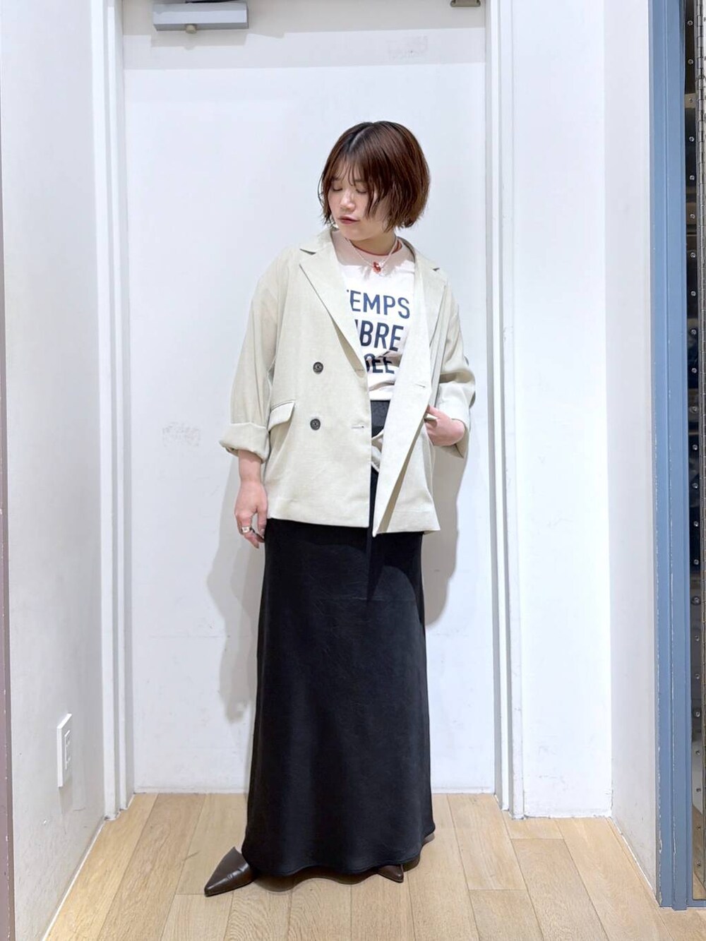 ブラック系のスカート、ベージュ系のその他アウター、ブラウン系のサンダルを着用したレディースの春コーディネートの2枚目の写真