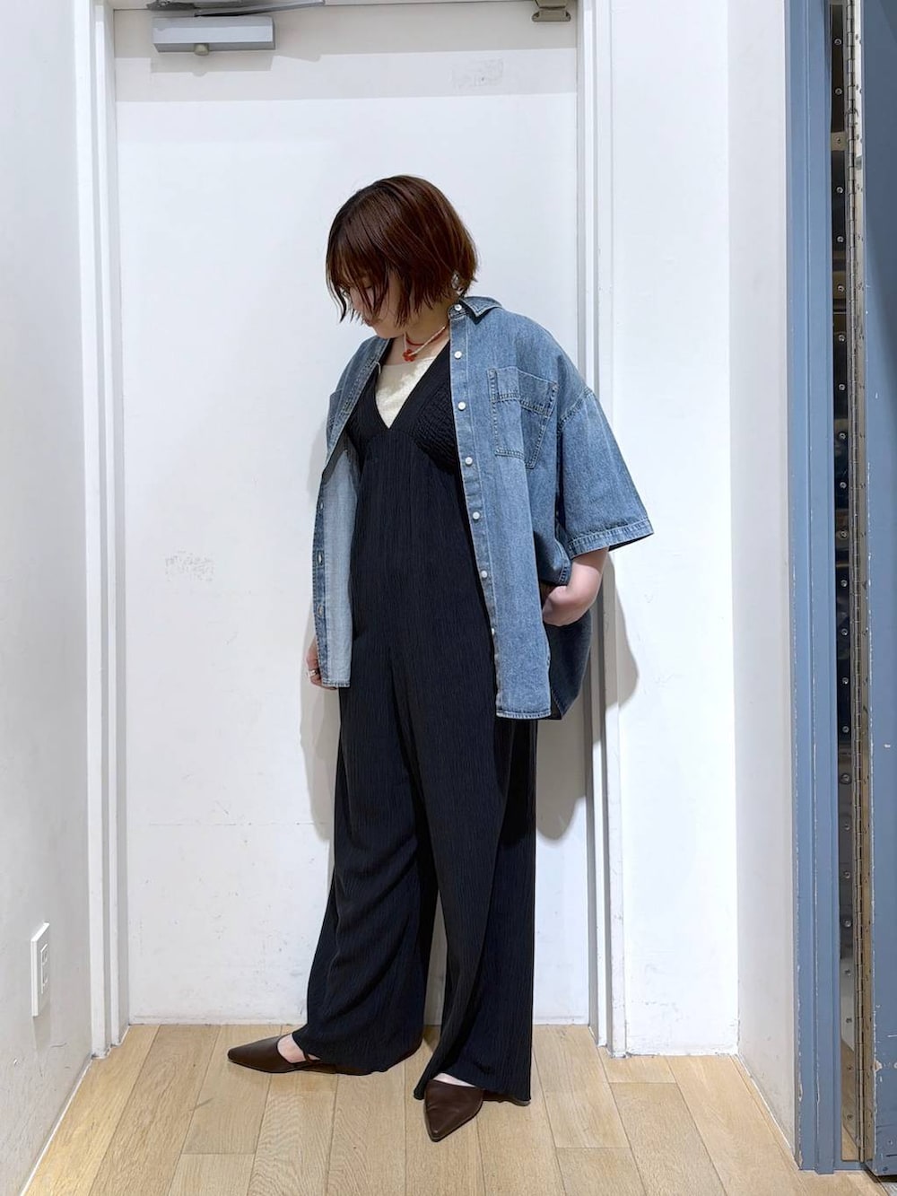 ブラック系のサロペット/オーバーオール、ゴールド系のタンクトップ、ブルー系のシャツ/ブラウスを着用したレディースの春コーディネートの4枚目の写真