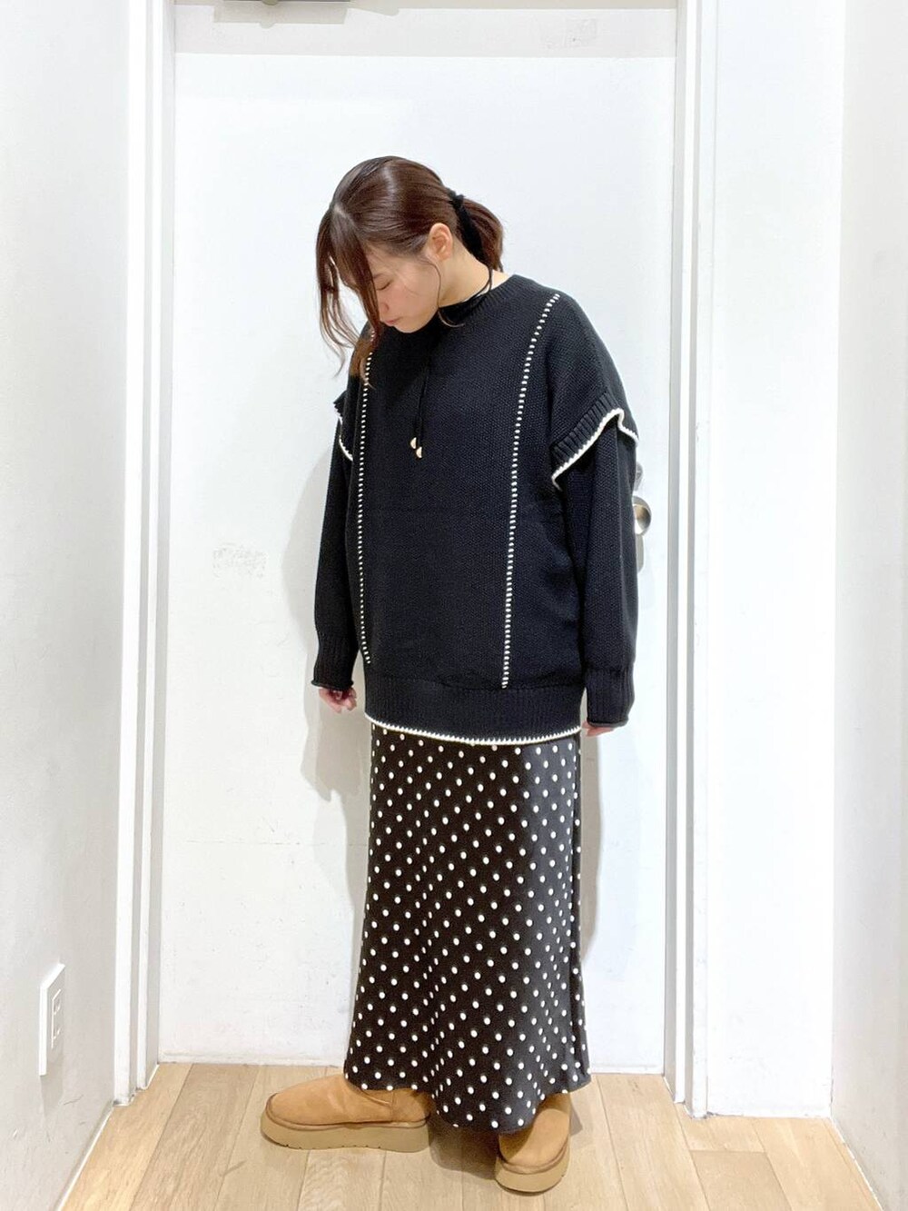 ブラック系のスカート、ブラック系のニット/セーター、ベージュ系のブーツを着用したレディースの秋コーディネートの2枚目の写真