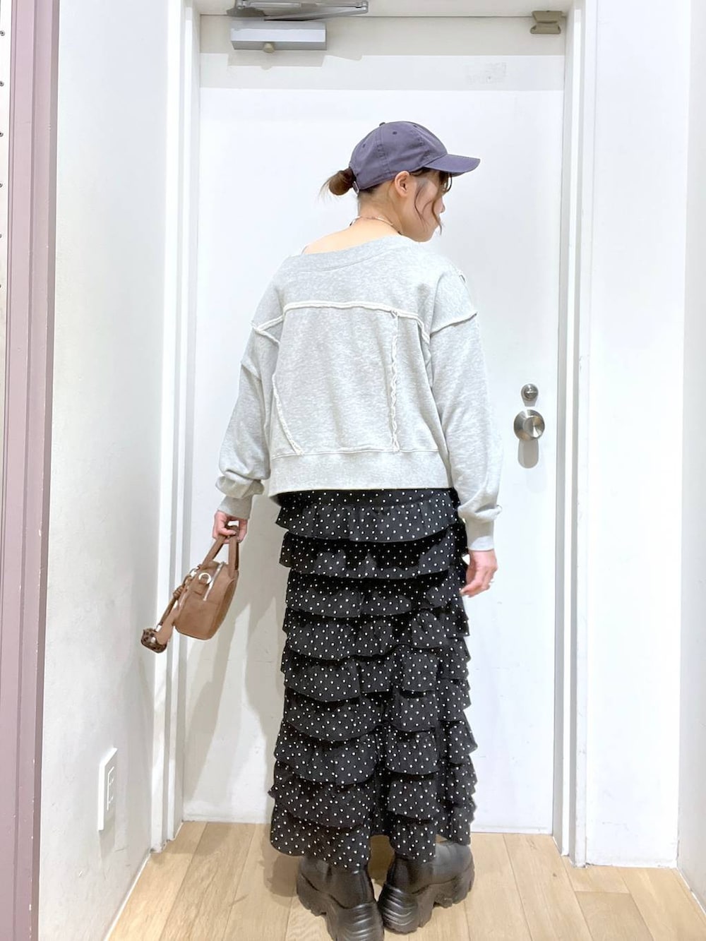 ブラック系のブーツ、グレー系のスウェット、ブラウン系のボストンバッグを着用したレディースの秋コーディネートの3枚目の写真