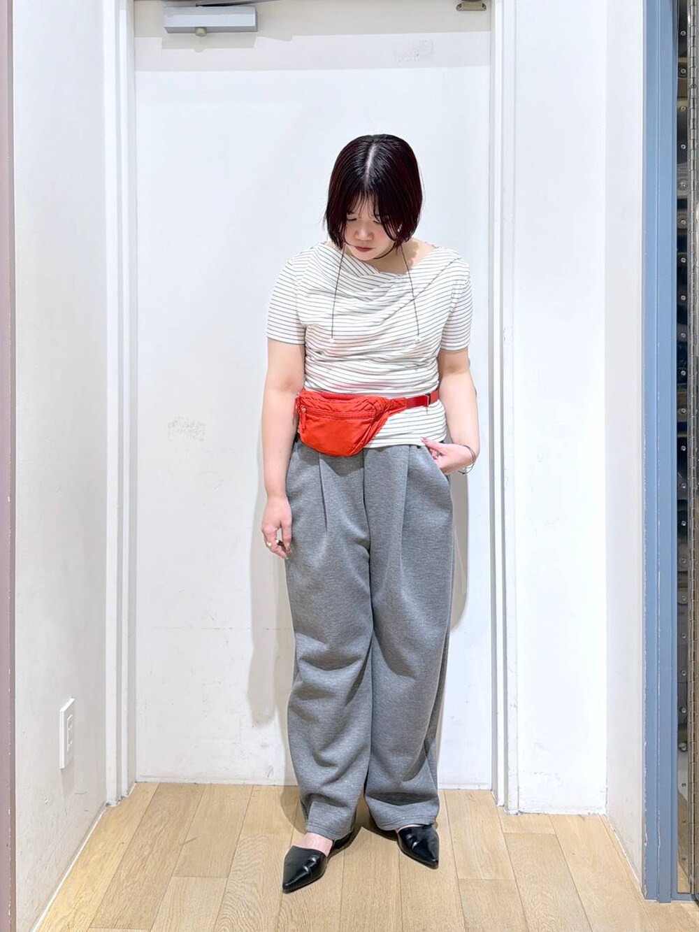 グレー系のスウェットパンツ、レッド系のボディバッグ/ウエストポーチ、ホワイト系のTシャツ/カットソーを着用したレディースの春コーディネートの2枚目の写真