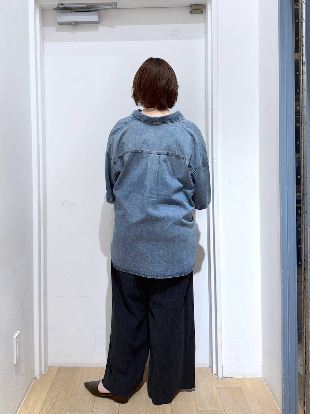 ブラック系のサロペット/オーバーオール、ゴールド系のタンクトップ、ブルー系のシャツ/ブラウスを着用したレディースの春コーディネートの5枚目の写真