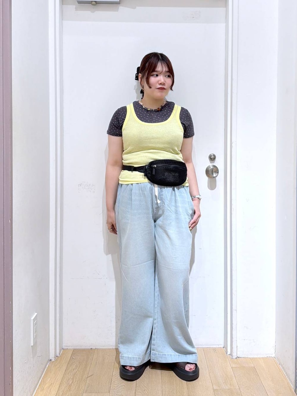 イエロー系のタンクトップ、ブラック系のボディバッグ/ウエストポーチ、グレー系のTシャツ/カットソーを着用したレディースの夏コーディネートの2枚目の写真
