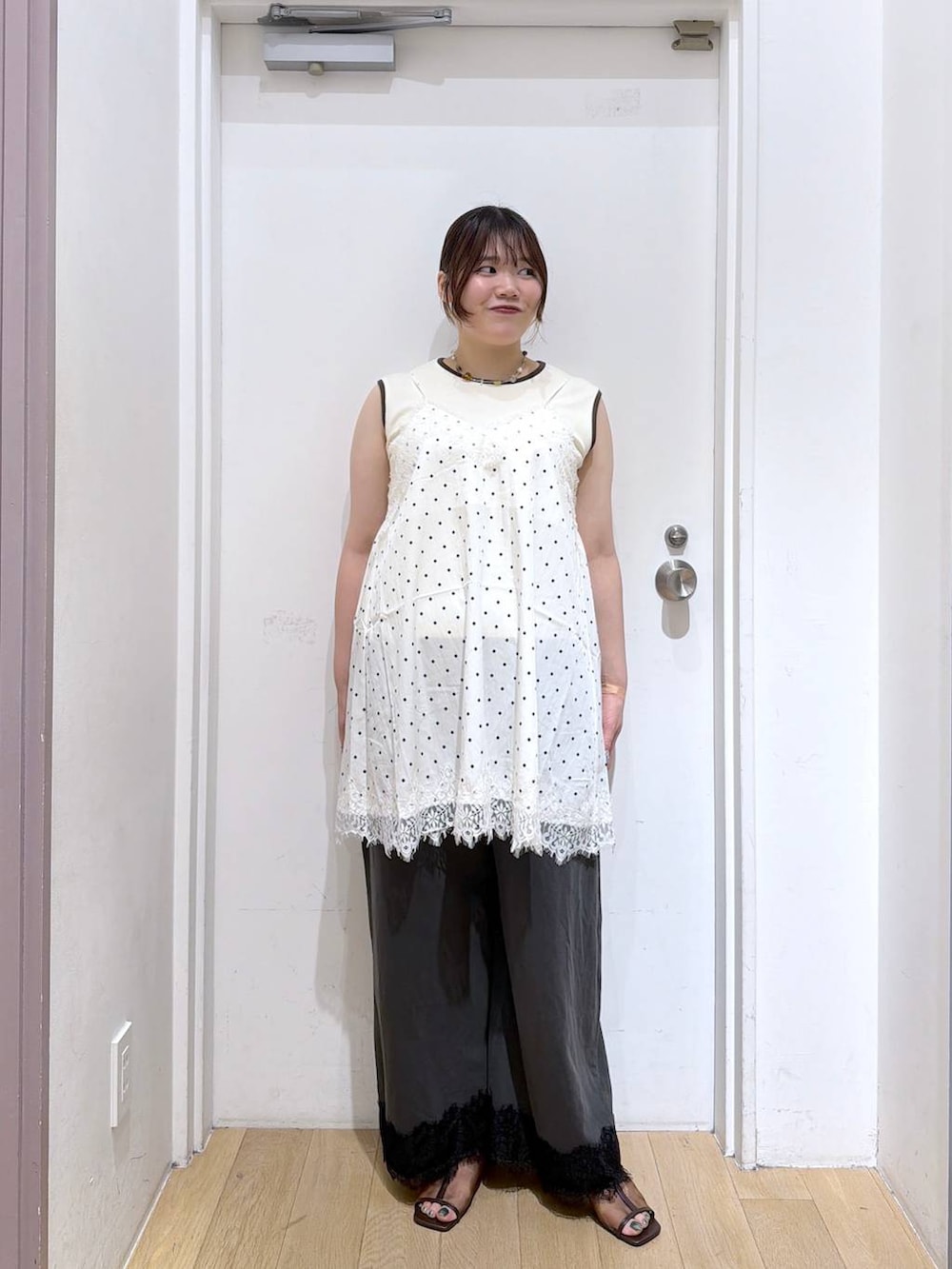 ホワイト系のタンクトップ、ブラウン系のサンダル、グレー系のスウェットパンツを着用したレディースの夏コーディネートの2枚目の写真