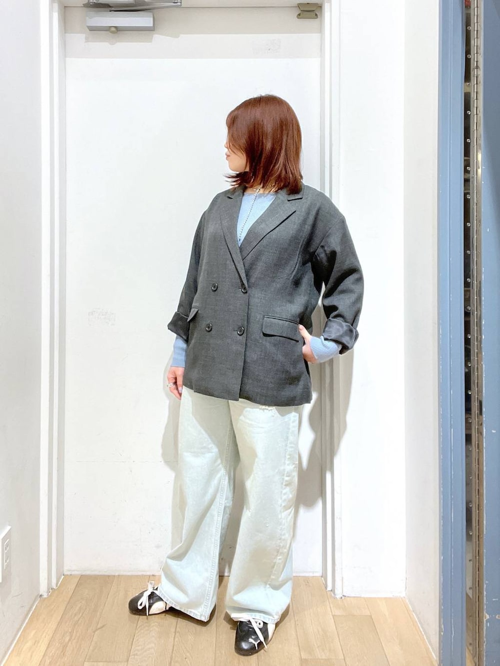 グレー系のテーラードジャケット、ブルー系のデニムパンツ、ブルー系のニット/セーターを着用したレディースの冬コーディネートの2枚目の写真