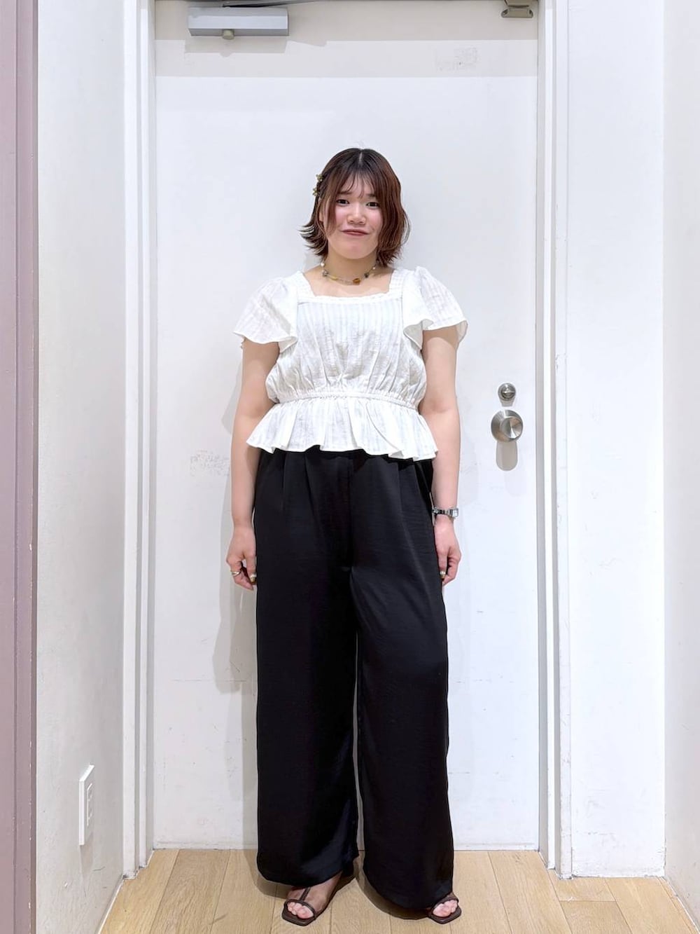 ブラック系のその他パンツ、ブラウン系のサンダル、ホワイト系のシャツ/ブラウスを着用したレディースの夏コーディネートの2枚目の写真