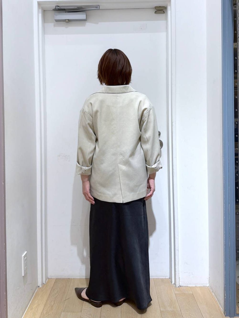 ブラック系のスカート、ベージュ系のその他アウター、ブラウン系のサンダルを着用したレディースの春コーディネートの3枚目の写真