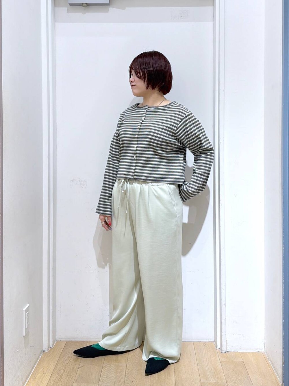 ブラック系のパンプス、グリーン系のその他パンツ、グレー系のカーディガン/ボレロを着用したレディースの春コーディネートの2枚目の写真