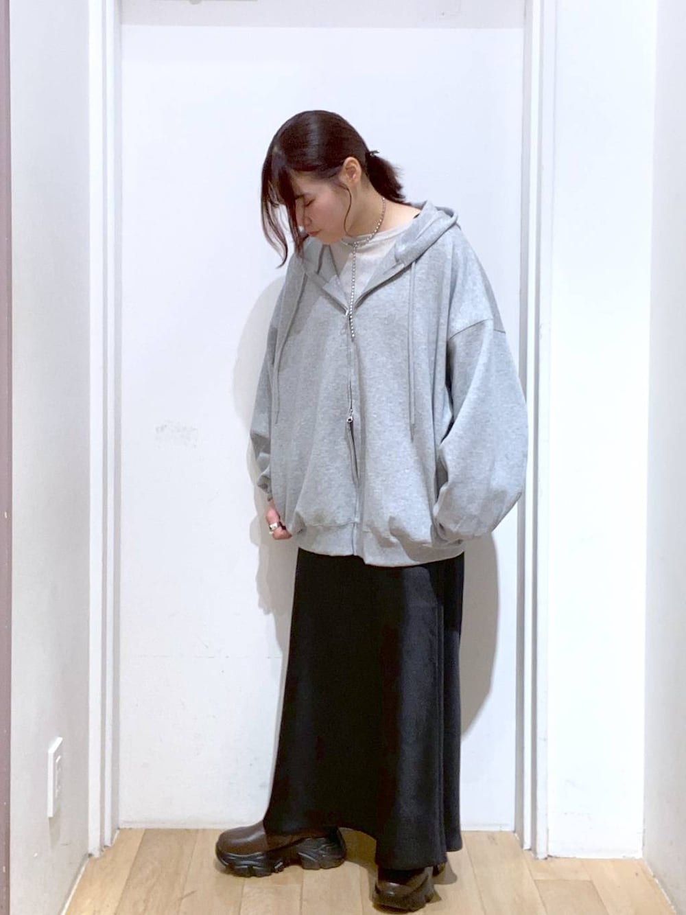 ブラウン系のブーツ、ブラック系のスカート、グレー系のパーカーを着用したレディースの秋コーディネートの2枚目の写真