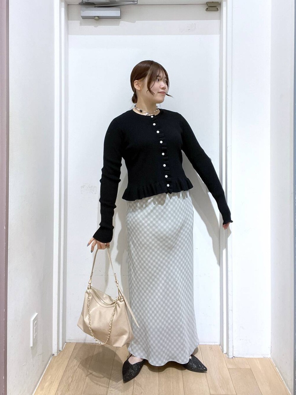 ベージュ系のショルダーバッグ、ブラック系のパンプス、ブラック系のTシャツ/カットソーを着用したレディースの冬コーディネートの2枚目の写真