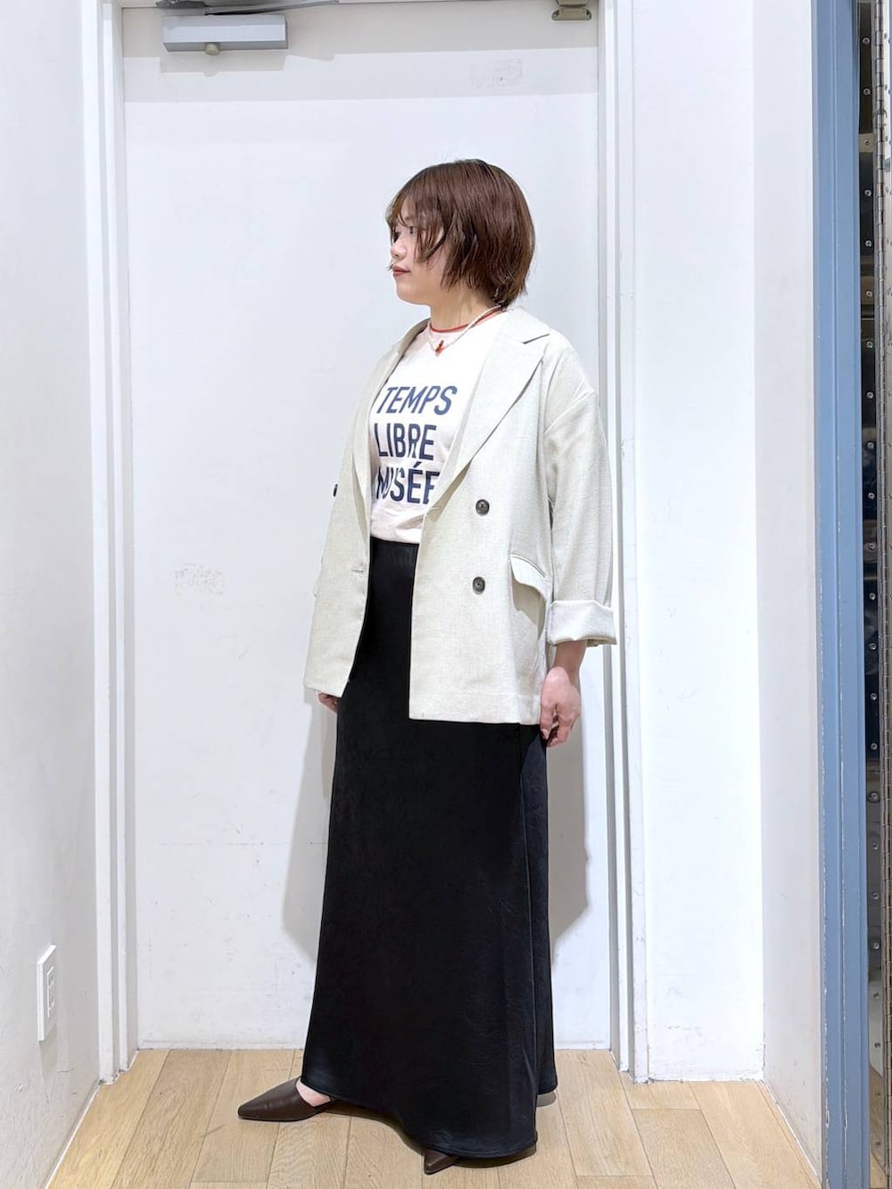 ブラック系のスカート、ベージュ系のその他アウター、ブラウン系のサンダルを着用したレディースの春コーディネートの4枚目の写真