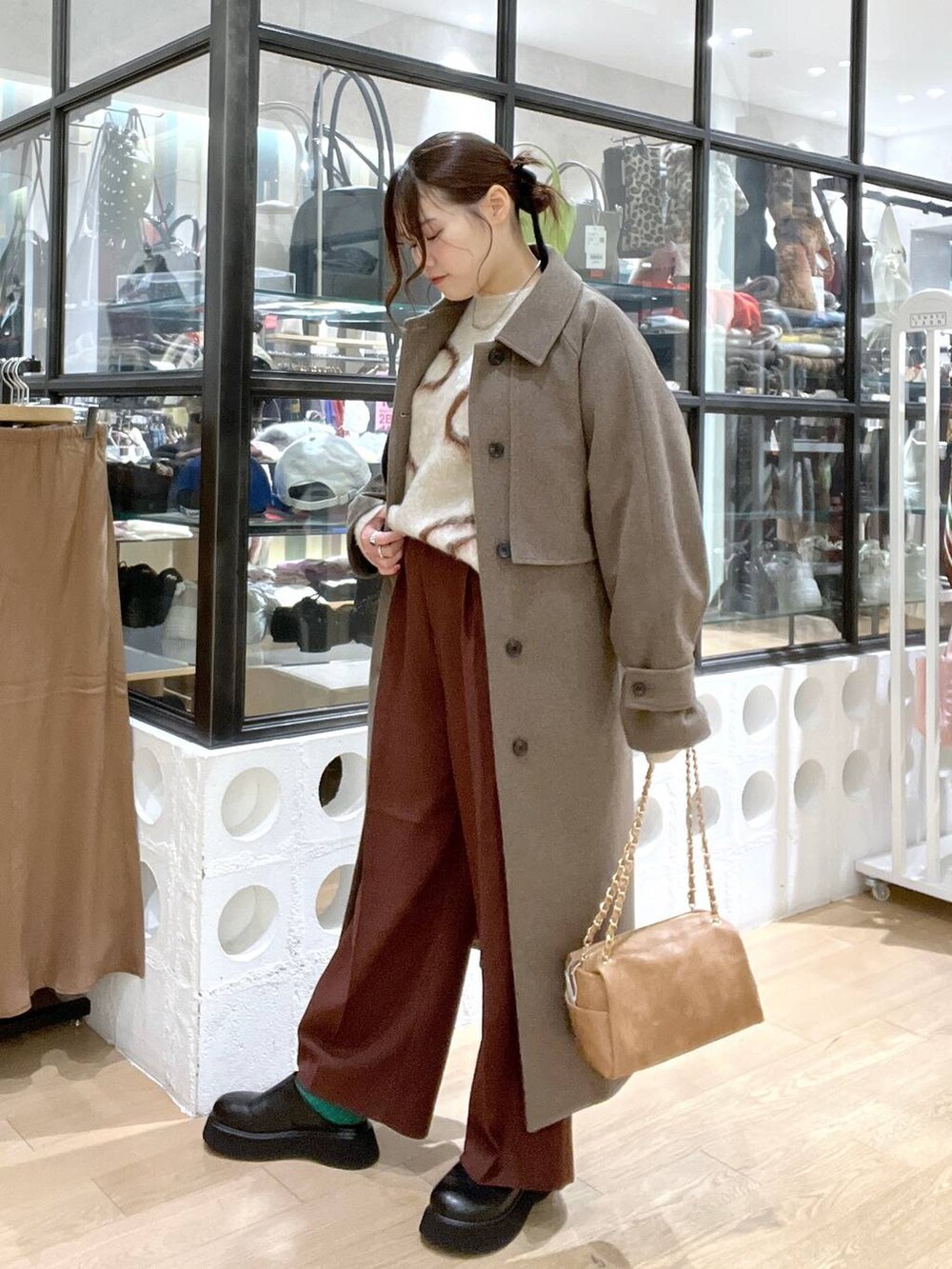 ブラウン系のステンカラーコート、ブラウン系のスラックス、ブラック系のサンダルを着用したレディースの冬コーディネートの2枚目の写真