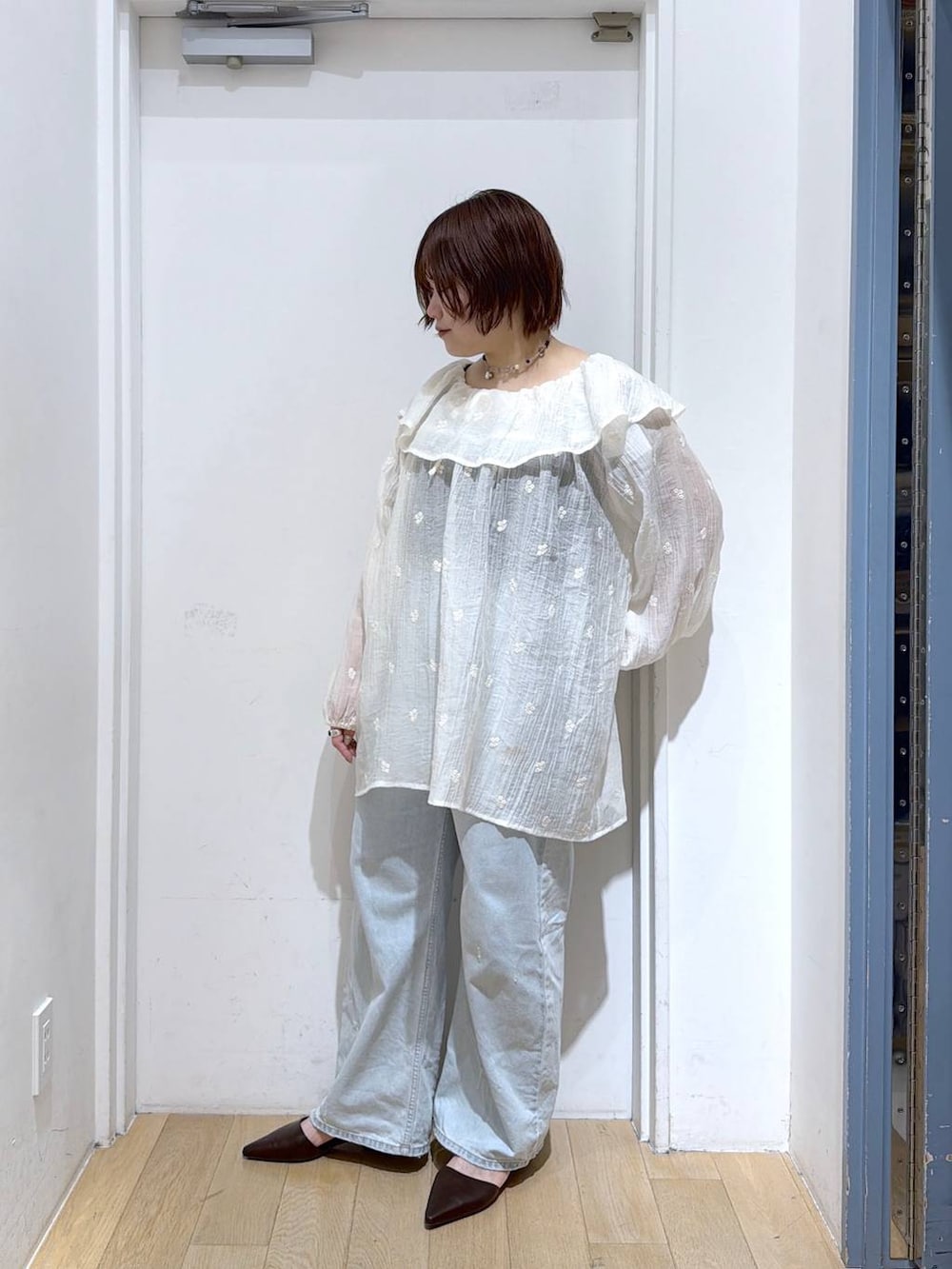 ブルー系のデニムパンツ、ブラウン系のサンダル、ホワイト系のワンピースを着用したレディースの春コーディネートの3枚目の写真