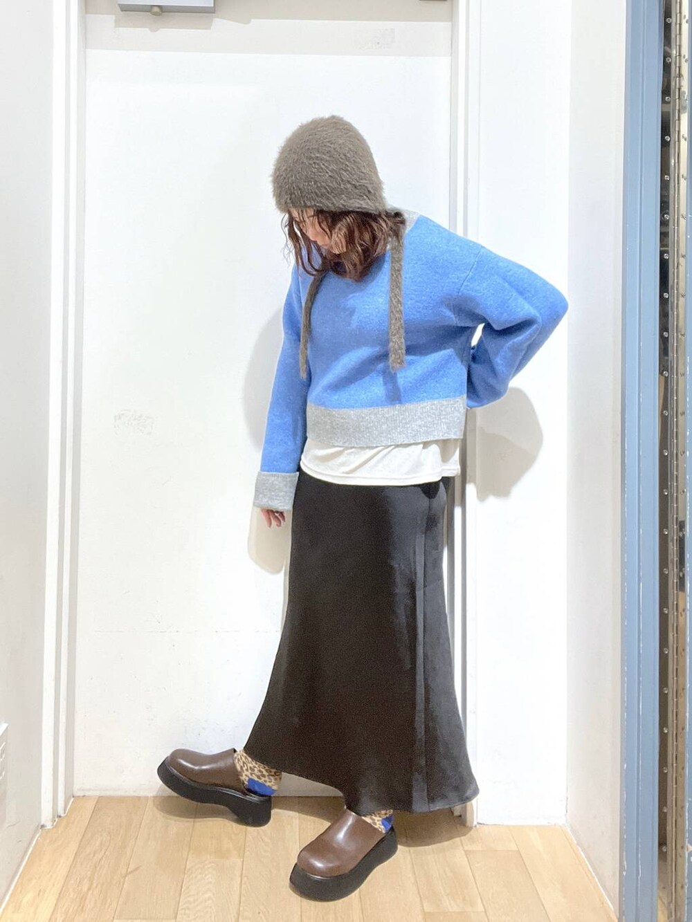 ブラック系のスカート、ブラウン系のサンダル、グレー系のニット/セーターを着用したレディースの冬コーディネートの2枚目の写真