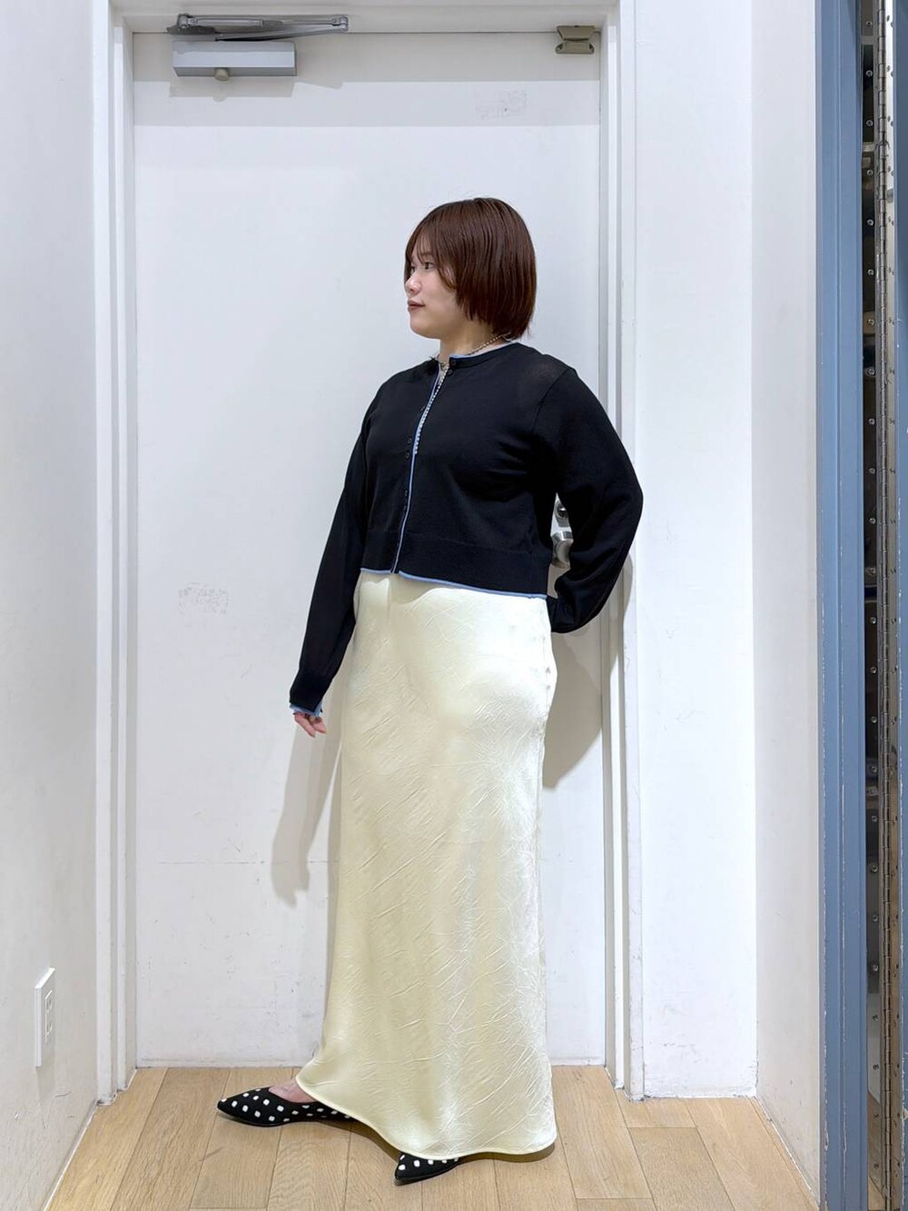 イエロー系のスカート、その他のパンプス、ブラック系のカーディガン/ボレロを着用したレディースの春コーディネートの3枚目の写真