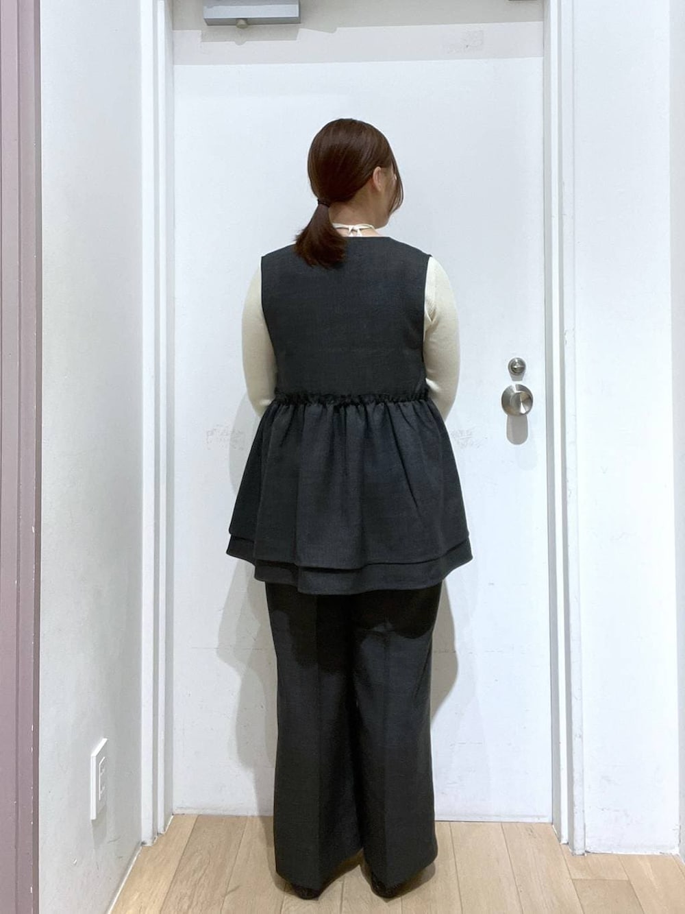 グレー系のデニムパンツ、グレー系のベスト、ブラック系のパンプスを着用したレディースの冬コーディネートの4枚目の写真