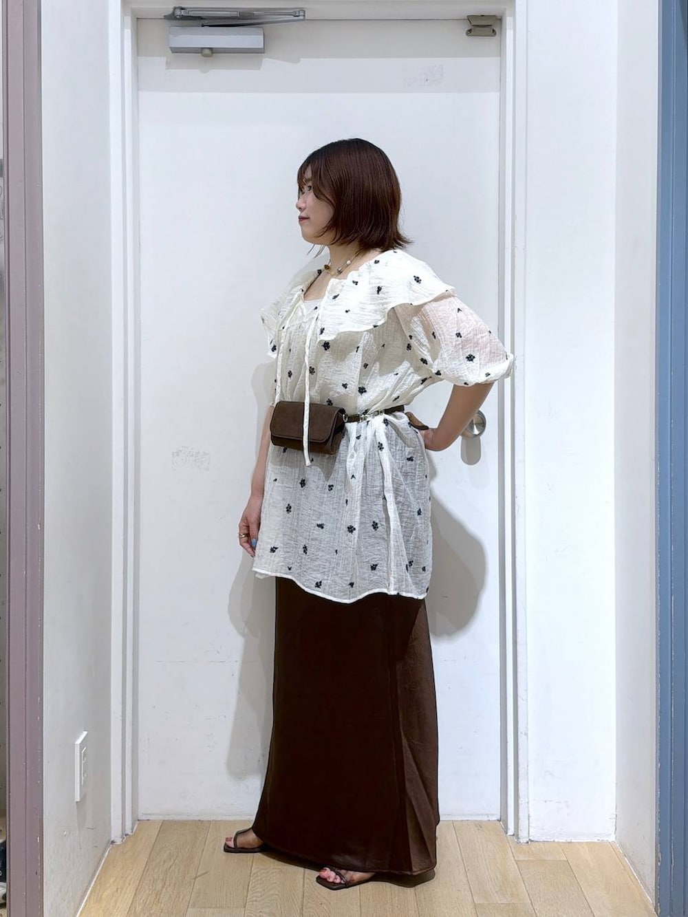 ホワイト系のワンピース、ブラウン系のスカート、シルバー系のタンクトップを着用したレディースの夏コーディネートの3枚目の写真