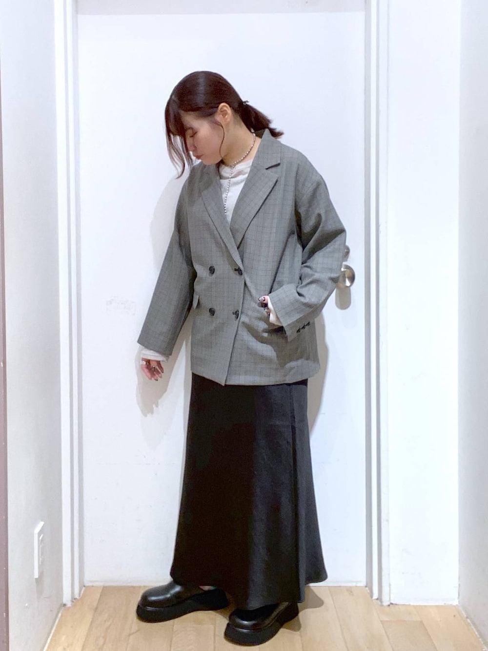 ブラック系のスカート、グレー系のテーラードジャケット、ブラック系のサンダルを着用したレディースの秋コーディネートの2枚目の写真