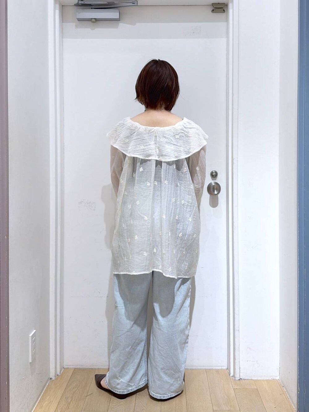 ブルー系のデニムパンツ、ブラウン系のサンダル、ホワイト系のワンピースを着用したレディースの春コーディネートの4枚目の写真