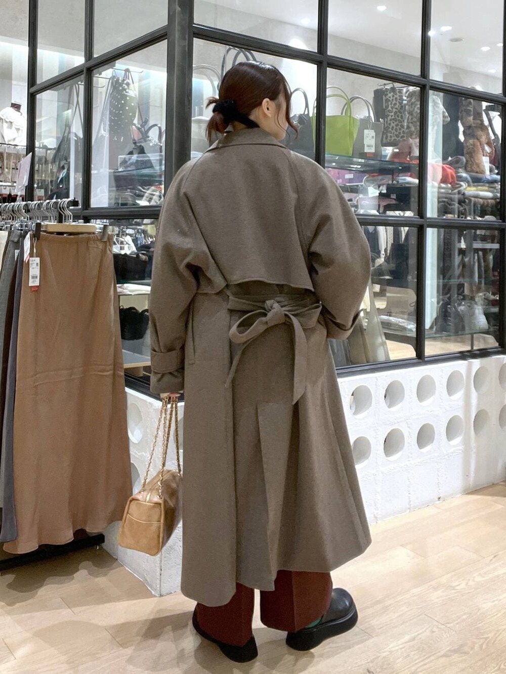 ブラウン系のステンカラーコート、ブラウン系のスラックス、ブラック系のサンダルを着用したレディースの冬コーディネートの3枚目の写真