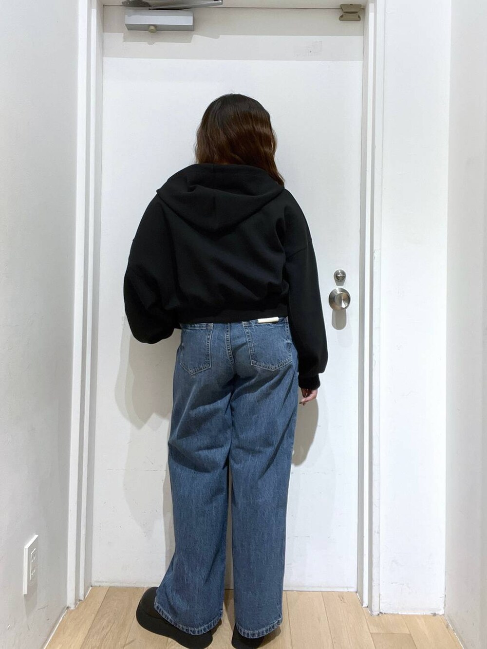 ブルー系のデニムパンツ、ブラック系のサンダル、ブラック系のパーカーを着用したレディースの秋コーディネートの3枚目の写真