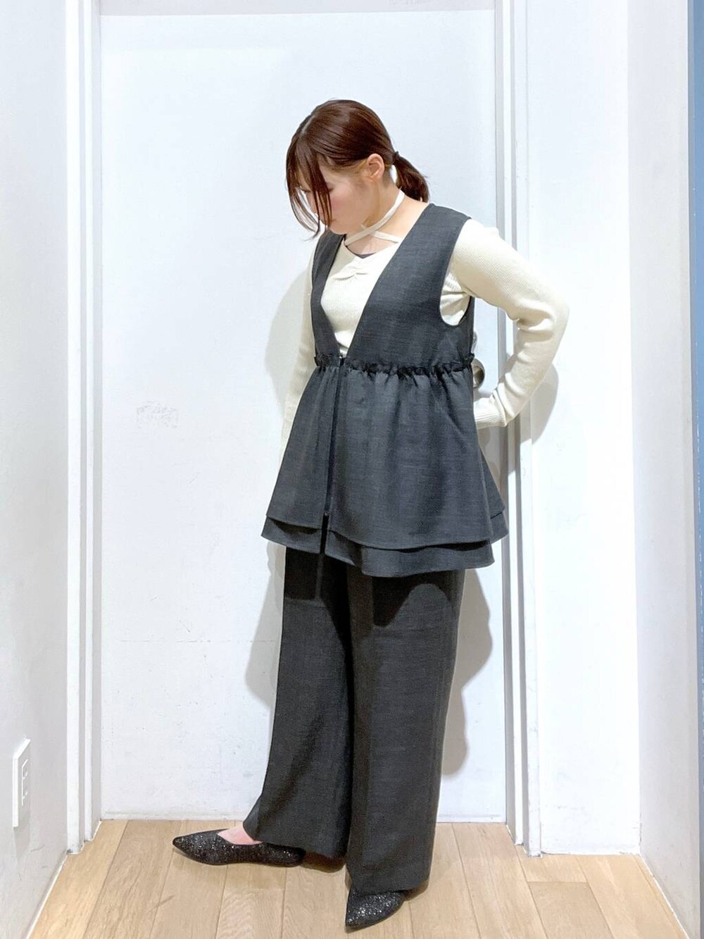 グレー系のデニムパンツ、グレー系のベスト、ブラック系のパンプスを着用したレディースの冬コーディネートの3枚目の写真