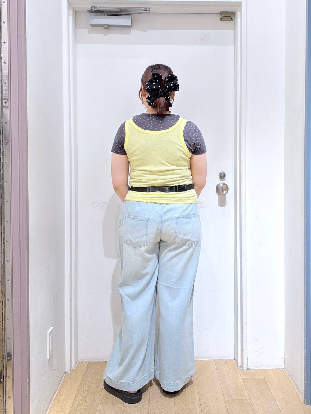 イエロー系のタンクトップ、ブラック系のボディバッグ/ウエストポーチ、グレー系のTシャツ/カットソーを着用したレディースの夏コーディネートの4枚目の写真