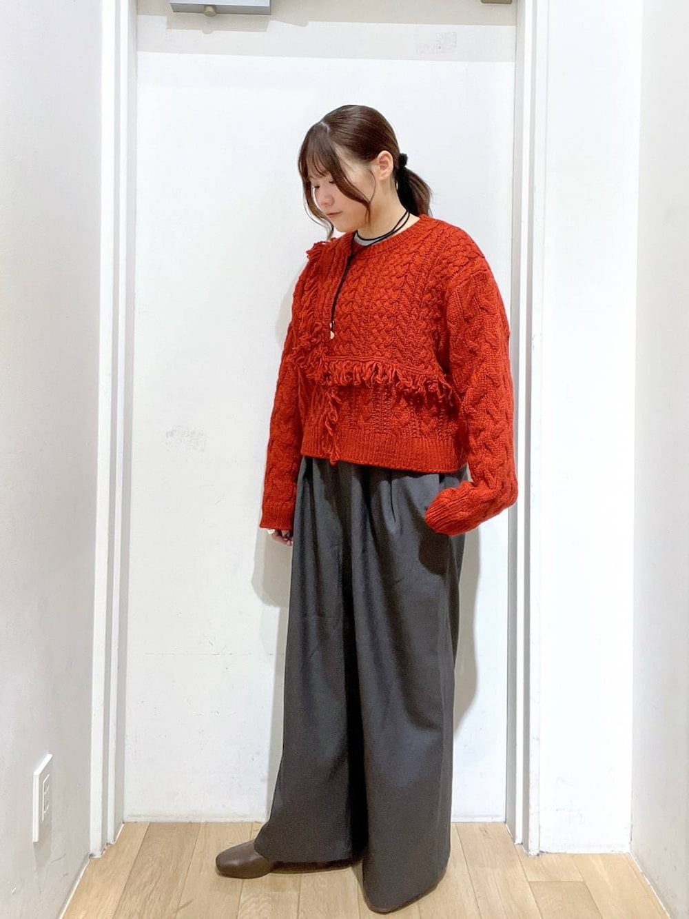 グレー系のその他パンツ、レッド系のポロシャツ、ブラウン系のブーツを着用したレディースの秋コーディネートの2枚目の写真