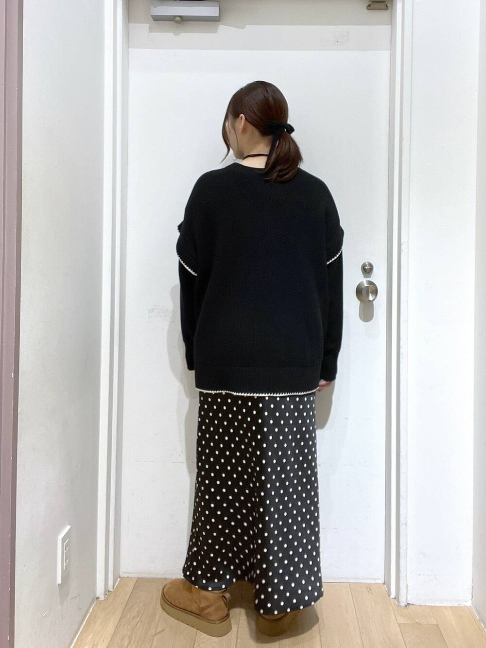 ブラック系のスカート、ブラック系のニット/セーター、ベージュ系のブーツを着用したレディースの秋コーディネートの3枚目の写真