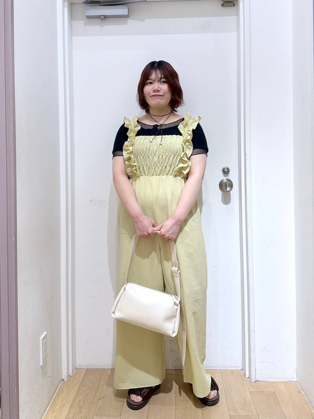 ブラウン系のサンダル、ホワイト系のショルダーバッグ、ブラック系のTシャツ/カットソーを着用したレディースの春コーディネートの2枚目の写真
