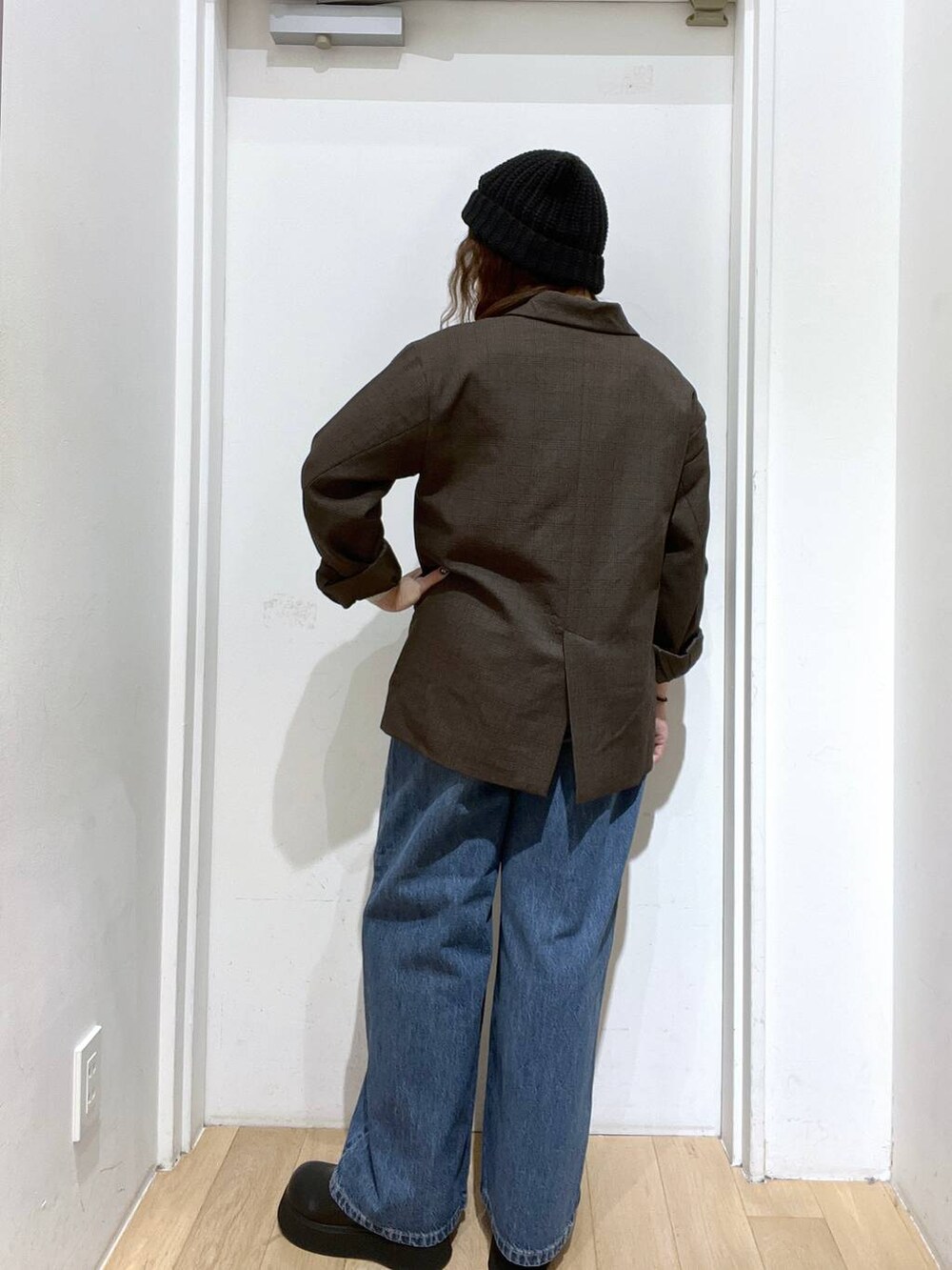 ブラウン系のテーラードジャケット、ブルー系のデニムパンツ、ブラック系のサンダルを着用したレディースの秋コーディネートの3枚目の写真