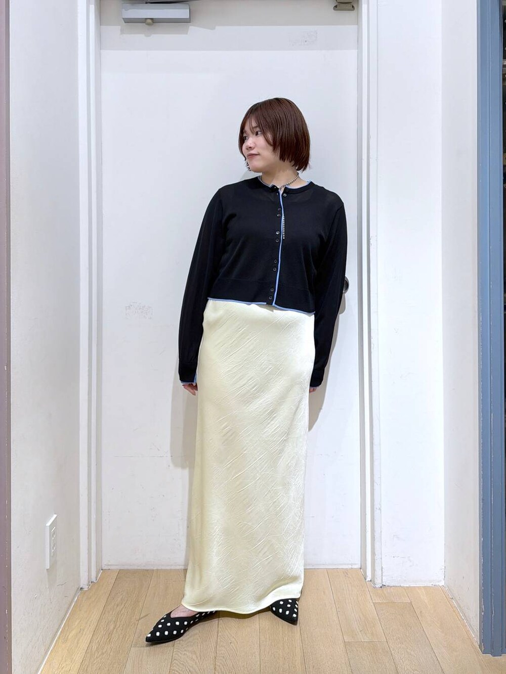 イエロー系のスカート、その他のパンプス、ブラック系のカーディガン/ボレロを着用したレディースの春コーディネートの2枚目の写真