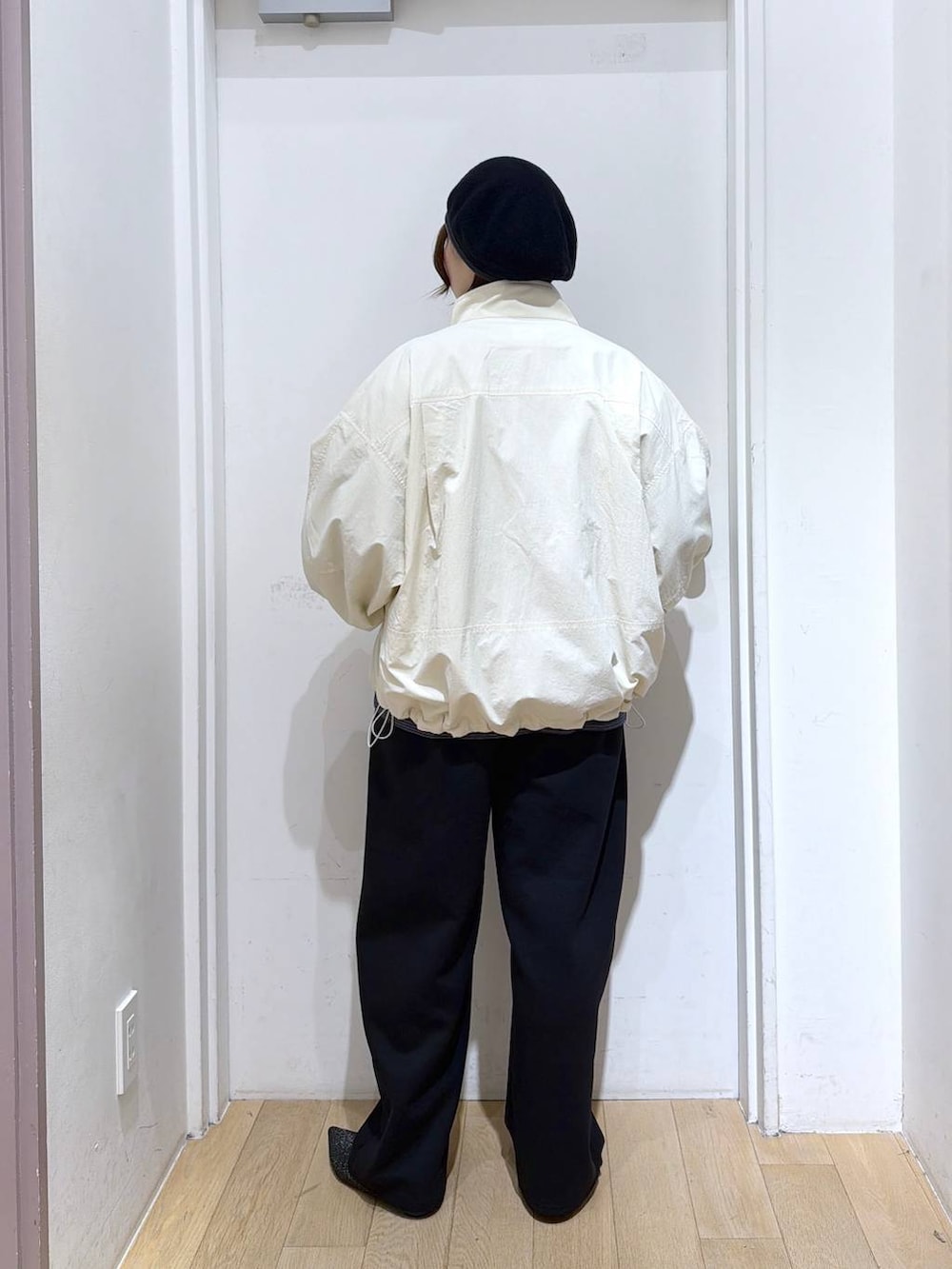 ホワイト系のナイロンジャケット、ブラック系のスウェットパンツ、ブラック系のパンプスを着用したレディースの冬コーディネートの3枚目の写真