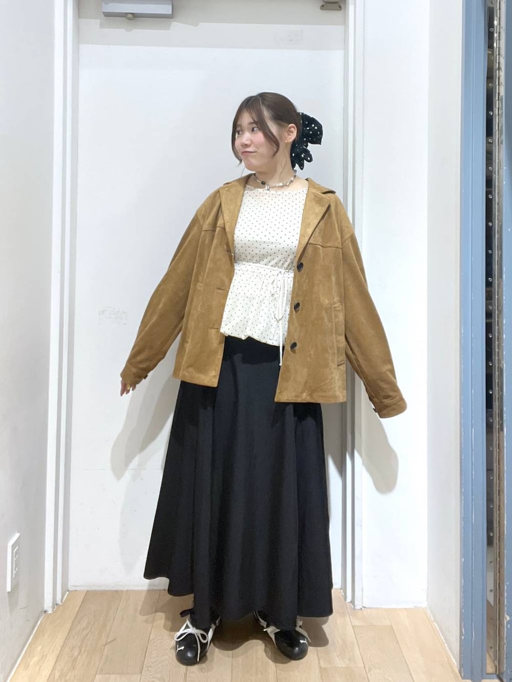 ブラウン系のテーラードジャケット、ホワイト系のTシャツ/カットソー、ブラック系のスカートを着用したレディースの冬コーディネートの2枚目の写真