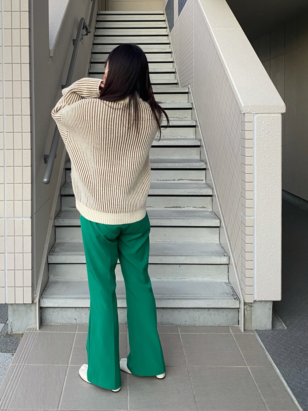 グリーン系のスラックス、ホワイト系のブーツ、ベージュ系のニット/セーターを着用したレディースの冬コーディネートの2枚目の写真