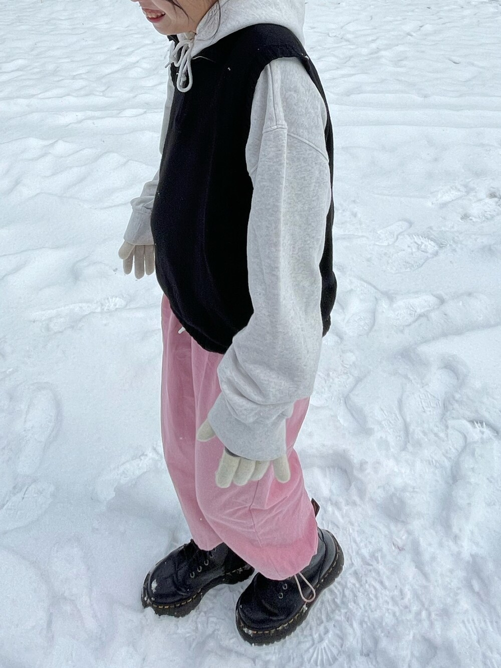 グレー系のパーカー、ブラック系のベスト、ピンク系のその他パンツを着用したレディースの冬コーディネートの2枚目の写真